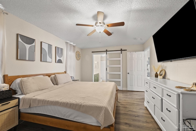 5576 Shadow Shore Pl, Gulf Breeze, FL 32563 - bedroom featuring a barn door, a textured ceiling, dark wood-style flooring, ensuite bathroom, and ceiling fan