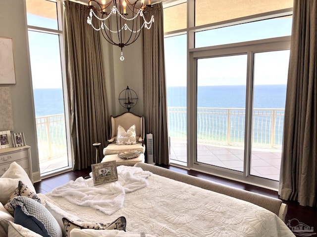 bedroom with access to outside, a chandelier, multiple windows, and a water view