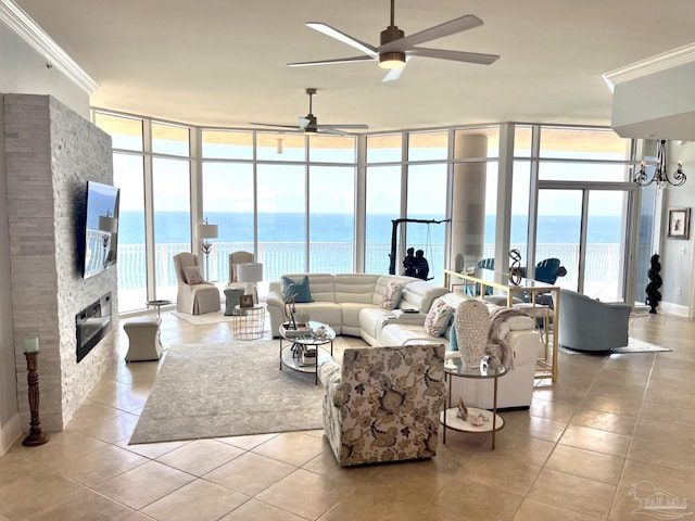 tiled living room with a fireplace, ceiling fan, a water view, plenty of natural light, and floor to ceiling windows