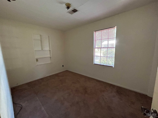 unfurnished room featuring built in shelves and carpet floors