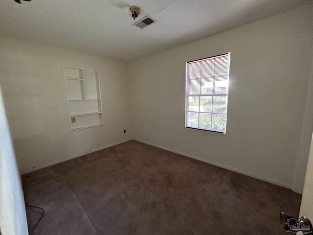 unfurnished room with built in shelves, carpet, and visible vents