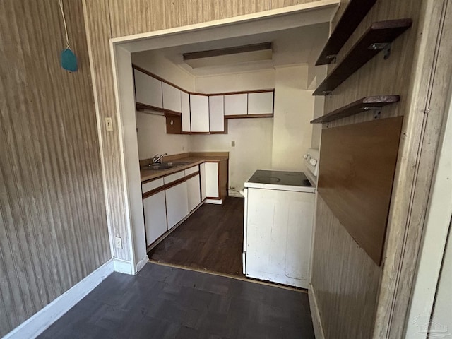 kitchen featuring electric range, baseboards, white cabinets, washer / clothes dryer, and a sink