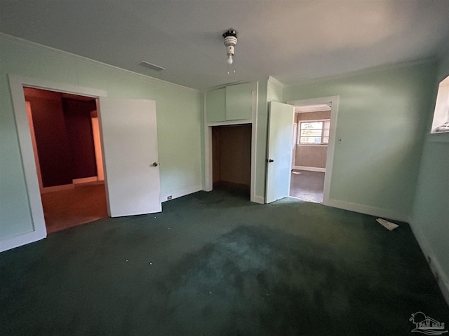 unfurnished bedroom with carpet, crown molding, a closet, visible vents, and baseboards