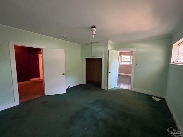 unfurnished bedroom featuring a closet, crown molding, and dark colored carpet