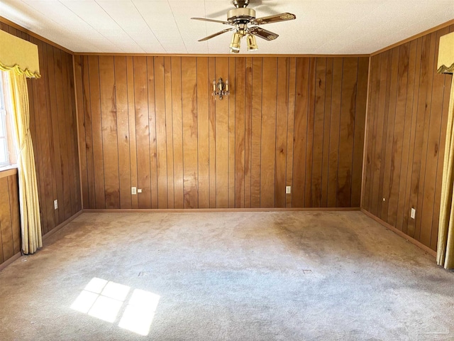 unfurnished room with carpet flooring, wooden walls, and ceiling fan