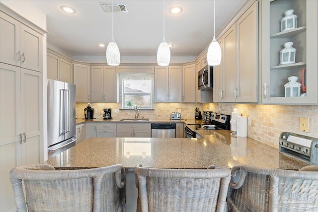 kitchen featuring appliances with stainless steel finishes, hanging light fixtures, sink, kitchen peninsula, and a breakfast bar area