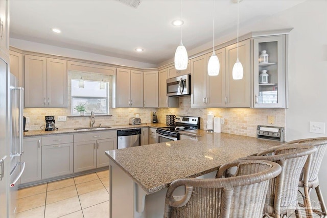 kitchen featuring kitchen peninsula, a kitchen breakfast bar, hanging light fixtures, sink, and stainless steel appliances