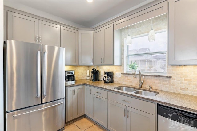 kitchen with sink, light stone counters, gray cabinetry, and stainless steel appliances