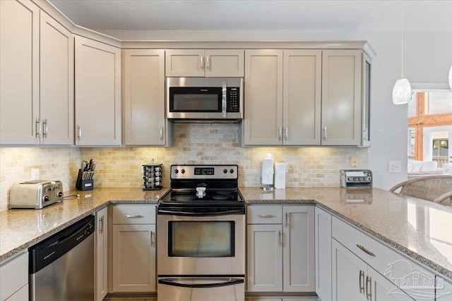 kitchen featuring stainless steel appliances, hanging light fixtures, decorative backsplash, and light stone counters