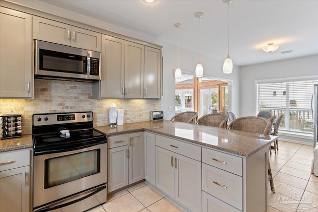 kitchen with pendant lighting, stainless steel appliances, kitchen peninsula, and a breakfast bar area