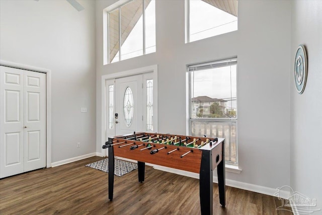 rec room with a wealth of natural light, a high ceiling, and dark hardwood / wood-style floors