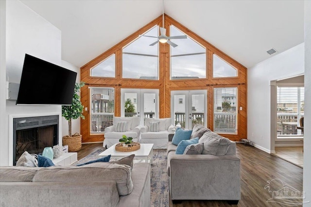 living room featuring high vaulted ceiling, a healthy amount of sunlight, wooden walls, and dark hardwood / wood-style flooring