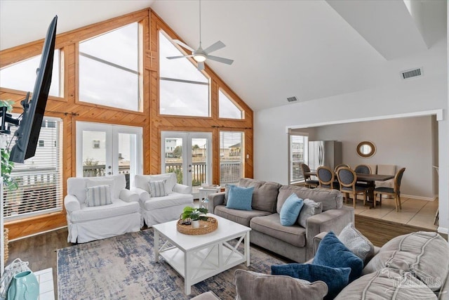 living room featuring wooden walls, french doors, high vaulted ceiling, dark wood-type flooring, and ceiling fan