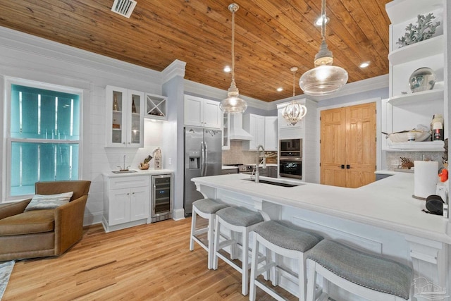 kitchen featuring pendant lighting, white cabinets, stainless steel refrigerator with ice dispenser, light hardwood / wood-style floors, and beverage cooler