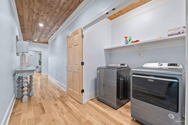 washroom featuring light hardwood / wood-style floors, crown molding, wooden ceiling, and washing machine and clothes dryer