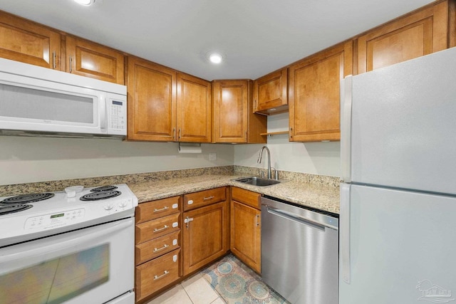 kitchen featuring sink, white appliances, light tile patterned floors, and light stone countertops