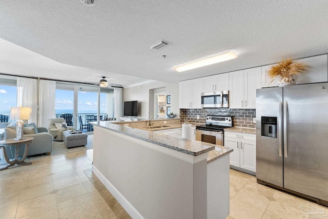 375 Beach Club Trl Unit A1801, Gulf Shores, AL 36542 - kitchen featuring stainless steel appliances, a peninsula, open floor plan, a sink, and white cabinetry