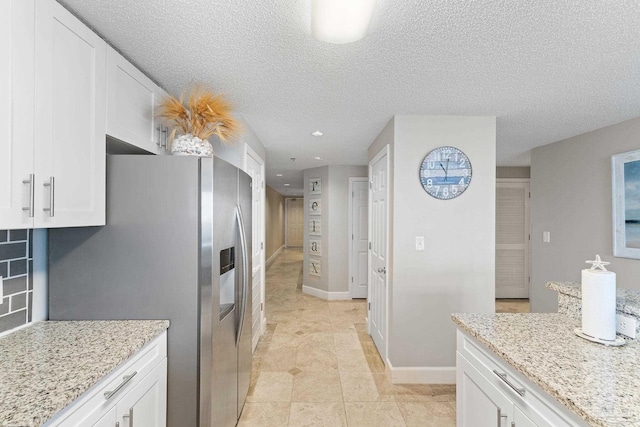 375 Beach Club Trl Unit A1801, Gulf Shores, AL 36542 - kitchen featuring stainless steel fridge with ice dispenser, white cabinets, light stone countertops, a textured ceiling, and baseboards