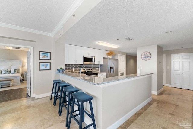 375 Beach Club Trl Unit A1801, Gulf Shores, AL 36542 - kitchen featuring appliances with stainless steel finishes, a textured ceiling, baseboards, decorative backsplash, and light stone counters