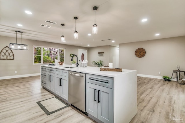 kitchen with sink, hanging light fixtures, stainless steel dishwasher, an island with sink, and gray cabinets