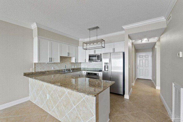 kitchen with white cabinetry, tasteful backsplash, kitchen peninsula, dark stone counters, and stainless steel appliances