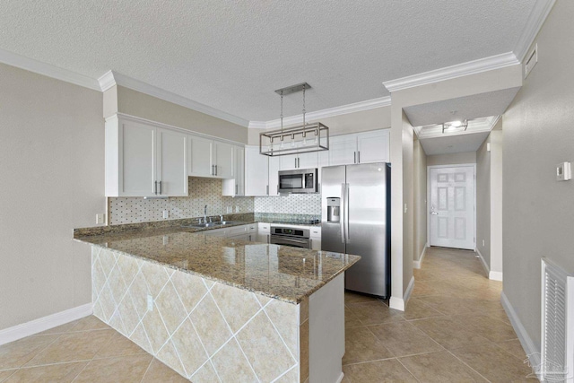 kitchen with sink, dark stone countertops, appliances with stainless steel finishes, kitchen peninsula, and white cabinets