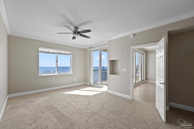 empty room featuring light carpet, a water view, a healthy amount of sunlight, and ceiling fan