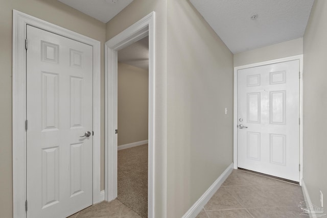 hall featuring light tile patterned flooring and a textured ceiling