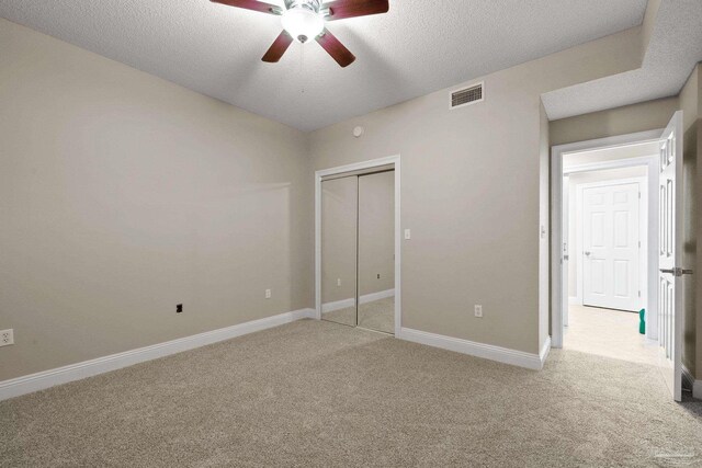 unfurnished bedroom featuring a textured ceiling, light carpet, ceiling fan, and a closet