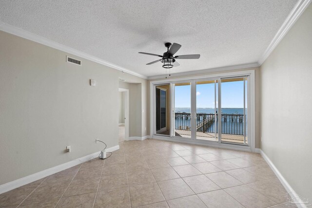 tiled empty room with a textured ceiling, a water view, ornamental molding, and ceiling fan