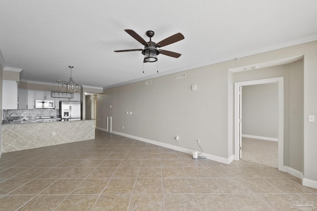 unfurnished living room with ornamental molding, ceiling fan with notable chandelier, light tile patterned floors, and a textured ceiling