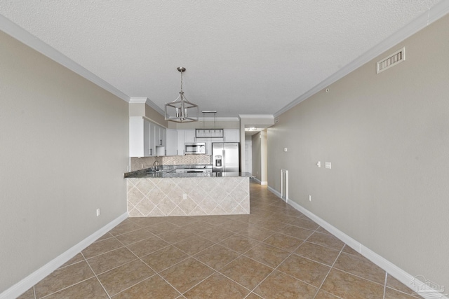 kitchen featuring appliances with stainless steel finishes, kitchen peninsula, white cabinets, pendant lighting, and backsplash