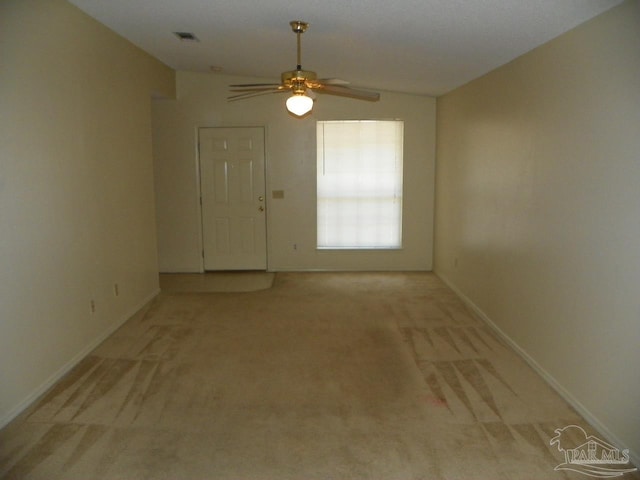 unfurnished room featuring lofted ceiling, visible vents, light carpet, ceiling fan, and baseboards