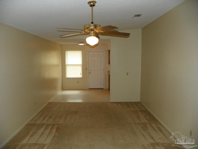 unfurnished room featuring light colored carpet, ceiling fan, visible vents, and baseboards