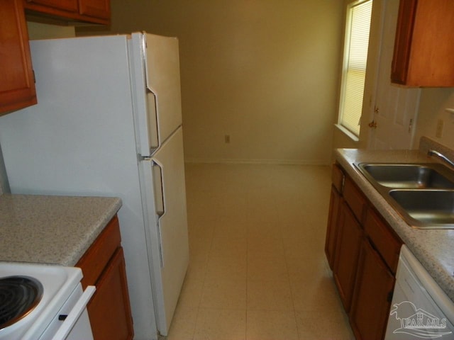 kitchen featuring brown cabinets, white appliances, light countertops, and a sink