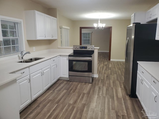 kitchen featuring stainless steel appliances, sink, white cabinets, and decorative light fixtures