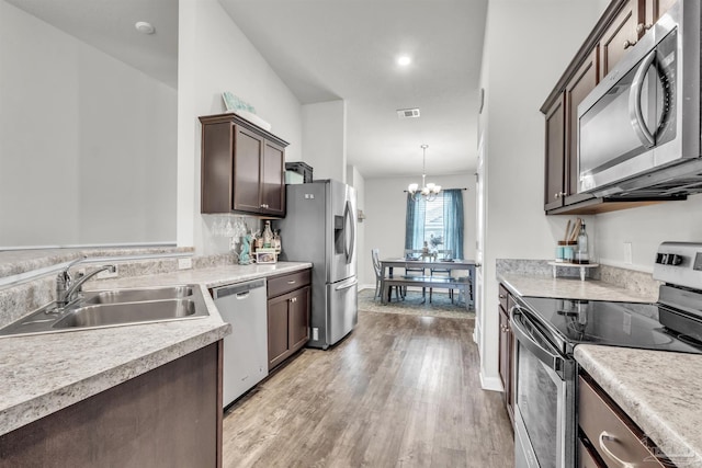 4744 Perception Cir, Milton, FL 32570 - kitchen featuring appliances with stainless steel finishes, dark brown cabinets, light wood-style floors, a chandelier, and light countertops