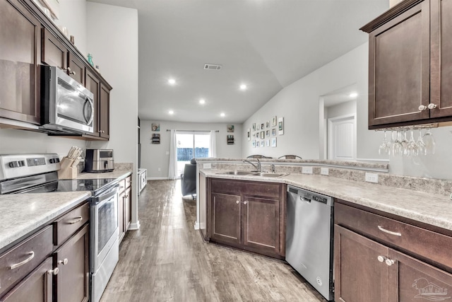 4744 Perception Cir, Milton, FL 32570 - kitchen with stainless steel appliances, light wood-type flooring, dark brown cabinetry, lofted ceiling, and recessed lighting