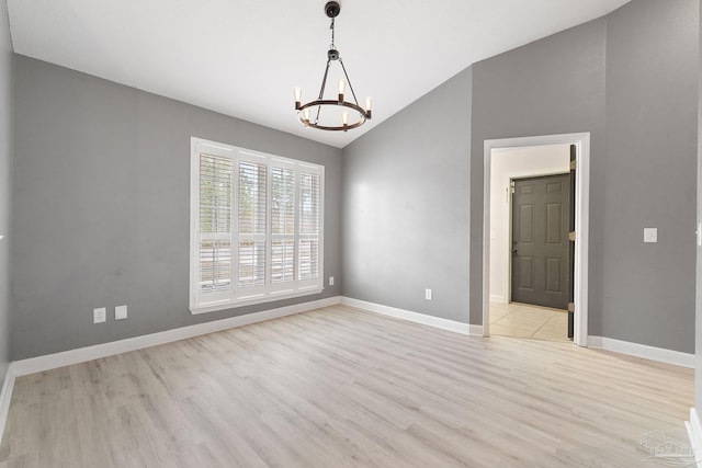 empty room with lofted ceiling, a notable chandelier, and light hardwood / wood-style flooring