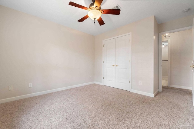 unfurnished bedroom featuring ceiling fan, light colored carpet, and a closet