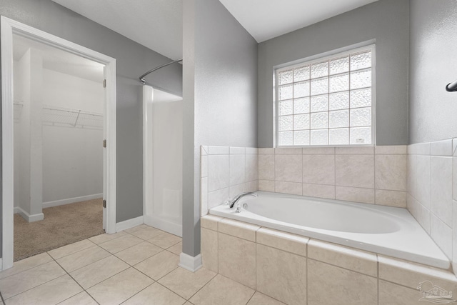 bathroom featuring tile patterned flooring and a relaxing tiled tub