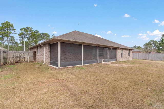 rear view of property featuring a yard and a sunroom