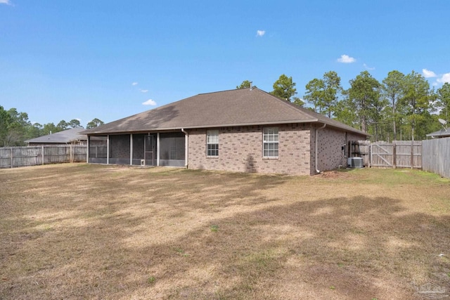 rear view of property with a sunroom, central AC, and a lawn