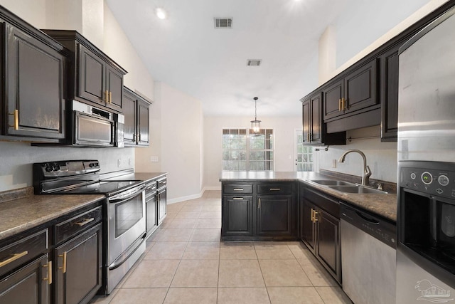 kitchen with sink, light tile patterned floors, hanging light fixtures, and appliances with stainless steel finishes