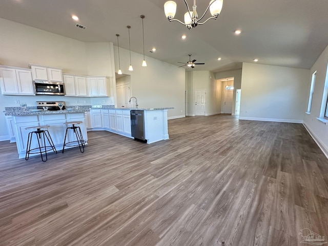 kitchen featuring stainless steel appliances, light stone countertops, hanging light fixtures, and white cabinets