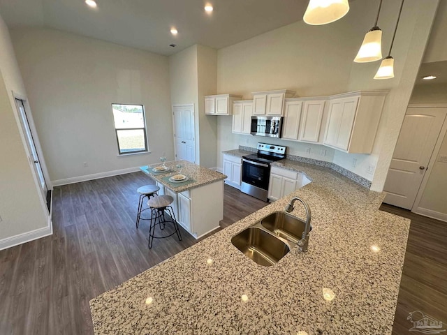 kitchen with decorative light fixtures, sink, white cabinets, a center island, and stainless steel appliances