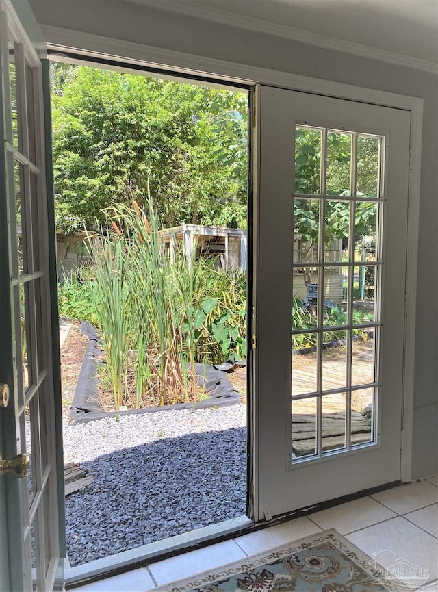 doorway to outside with tile patterned floors, ornamental molding, and plenty of natural light