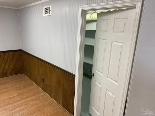 corridor featuring hardwood / wood-style flooring, wood walls, and ornamental molding