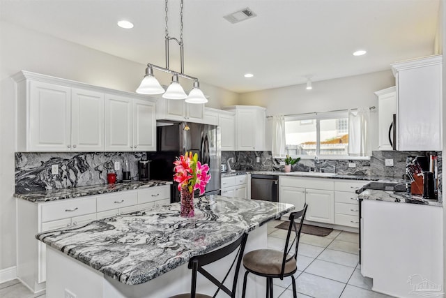 kitchen with a kitchen island, sink, stainless steel appliances, backsplash, and white cabinets