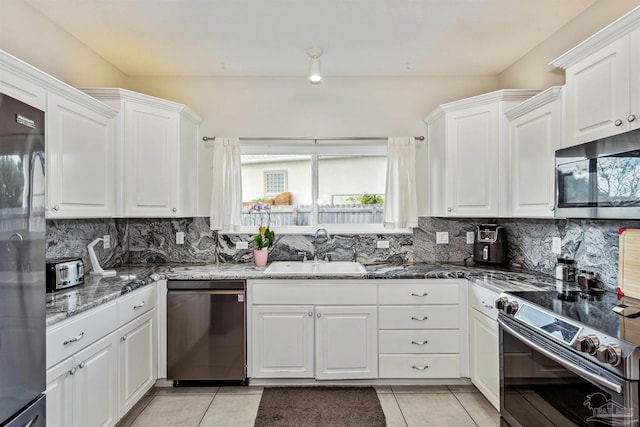 kitchen featuring dark stone countertops, white cabinets, appliances with stainless steel finishes, and sink